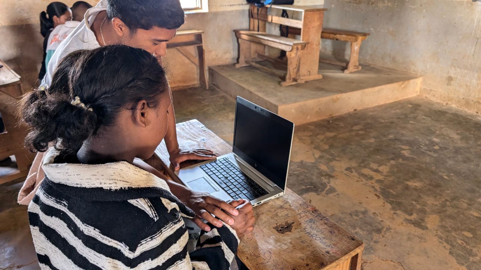 A trainer guiding a student through her first computer session, 2024