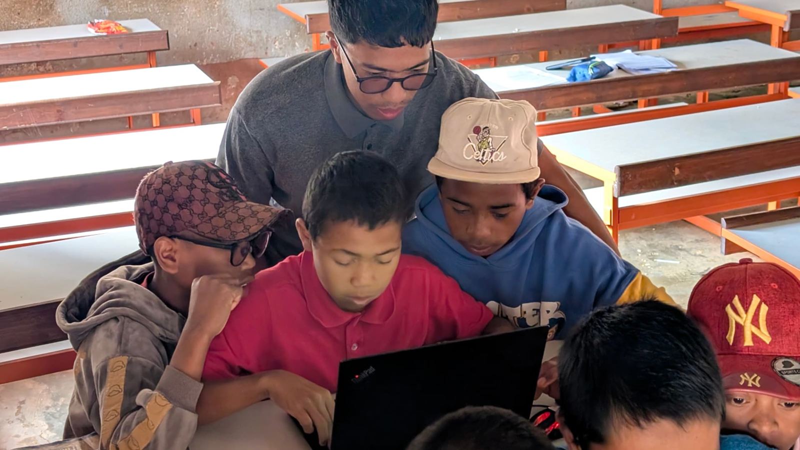 A trainer and students around a laptop during an ongoing 2026 session