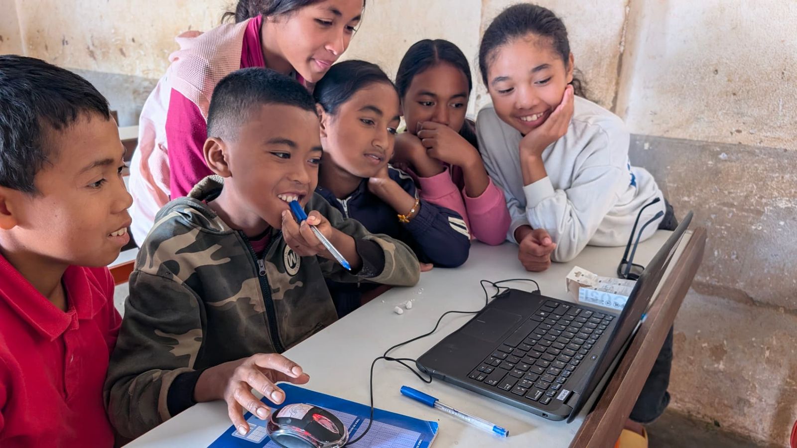 A group of students laughing around a laptop during a 2026 session